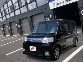 カーマッチ岩手盛岡店の店舗前に停車している、黒（ブラックマイカメタリック）のダイハツ・タント。フロントグリルがシルバーで、フォグランプ付きのスタイリッシュな外観。