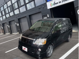 黒のトヨタ ノア（AZR60G）が店舗前に停車している外観写真。両側スライドドアのミニバンで、街中でも扱いやすいサイズ感のファミリー向け車両。