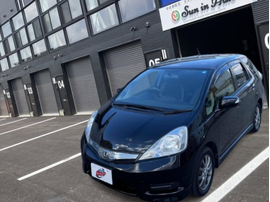 カーマッチ岩手盛岡店の店舗前に駐車された、黒のホンダ・フィットシャトルハイブリッドのフロント外観写真