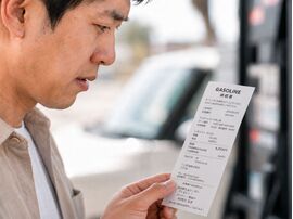 ガソリン代の値上がりを気にしながら給油レシートを確認する男性と、淡路島での燃料費や燃費のよいコンパクトカーへの乗り換えを考えるイメージ。
