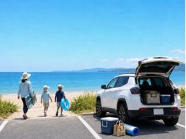 淡路島の海辺で、コンパクトカーにアウトドア用品を積み、親子で海水浴を楽しむ夏のレジャーシーン。コンパクトカーの積載性とアウトドアでの使いやすさをイメージした写真。