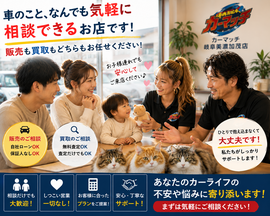小さな子供連れの夫婦が中古車販売・買取店でワイルドな男性スタッフとギャル風女性スタッフに安心した表情で相談している温かい接客シーンと3匹の猫