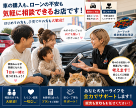 子連れの若い夫婦が中古車販売・買取店でショートヘアの女性スタッフに笑顔で相談しているリアルな接客シーンと3匹の猫