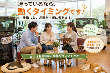 明るい中古車販売店の店内でソファに座りながらスタッフと男女のお客様がリラックスして会話し車購入について前向きに相談している決断前の自然な商談シーンと足元でくつろぐ猫たち