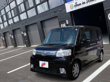 カーマッチ岩手盛岡店の店舗前に停車している、黒（ブラックマイカメタリック）のダイハツ・タント。フロントグリルがシルバーで、フォグランプ付きのスタイリッシュな外観。