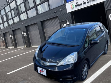 カーマッチ岩手盛岡店の店舗前に駐車された、黒のホンダ・フィットシャトルハイブリッドのフロント外観写真
