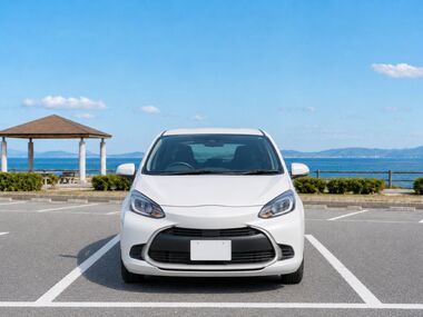 淡路島の海辺の観光地駐車場で、区画の中央に停められた白いコンパクトカー。
