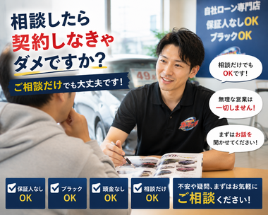 明るい中古車販売店の相談スペースで男性スタッフがお客様に寄り添いながら車購入や無料査定について丁寧に説明しているリアルな相談シーン